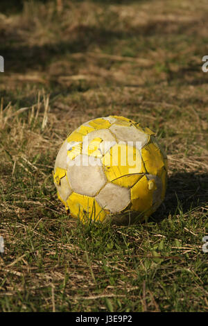 Leuchtend gelbe alte Fußball auf dem Rasen liegen und warten auf die Wirkung. Stockfoto