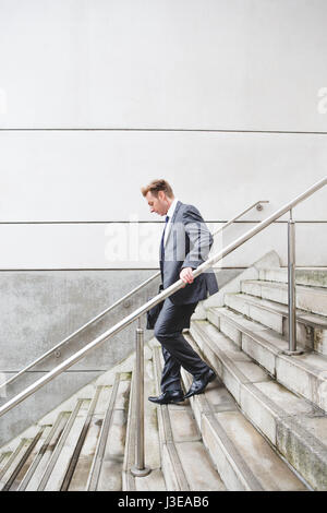 Geschäftsmann auf dem Weg zur Arbeit. Er geht ist in einem formellen Anzug gekleidet und einige Stufen hinunter. Stockfoto