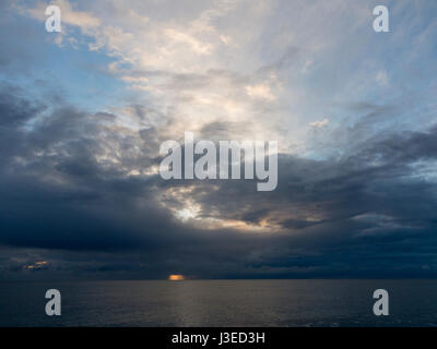 Sonnenaufgang hinter dunklen böse Wolken über der Nordsee Horizont als Hot Spot der orange Licht zu schaffen Stockfoto