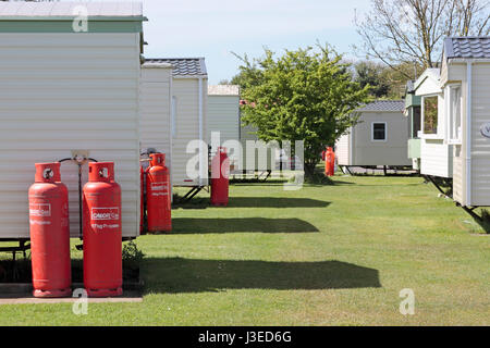 Reihen von jedem Wohnwagen mit zwei 47kg Calor Gasflaschen auf einem Ferienpark Wohnwagen eingehakt Stockfoto