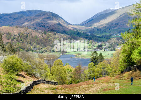 Ein paar Wanderer einen Hügel hinunter zum See Grasmere an einem sonnigen Tag im Frühling, Lake District, Cumbria, England. Stockfoto