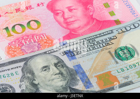 Chinesische Renminbi 100 und 100 US-Dollar Rechnungen gestapelt auf einem weißen Hintergrund. Stockfoto