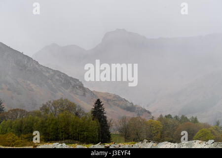 Verschwommenen Umriss des Langdale Gipfel an einem nebligen Tag im Frühling, gesehen vom Elterwater, Lake District, Cumbria, England. Stockfoto