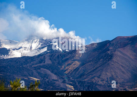 Ätna, ein aktiver Stratovulkan, aus dem Süden mit dem Rauchen Höhepunkt, schneebedeckten Flanken, eine seitliche Krater in der Mitte und eine Cable Car-Linie in der Pr Stockfoto