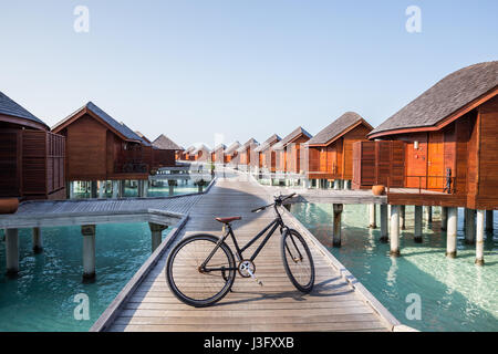 Exotischen tropischen Paradies Bike Fahrrad über Boardwalk über Wasser Bungalow flach Crystal Clear türkis blaue Meer Wasser Stockfoto