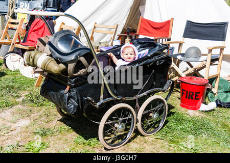Gruß an die 40er Re-enactment Veranstaltung. Baby im Kinderwagen mit Gasmaske hängen von Lenker. Puppe auf Viewer. Stockfoto