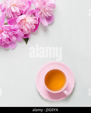 Tasse Tee und Pfingstrosen auf grauen Leuchttisch. Stockfoto