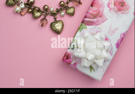 Hintergrund mit goldenes Herz und Perlenkette, rose Geschenk verpackt Gegenwart auf rosa Hintergrund - Liebe Hintergrund isoliert Stockfoto