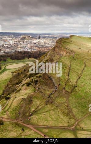 Eine Menge von Menschen Fuß auf Salisbury Crags, steigt spektakulär im Holyrood Park aus dem Stadtbild von Edinburghs Altstadt und Schloss. Stockfoto