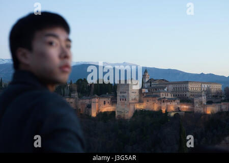 Asiatische Touristen vor der Alhambra-Palast im Bild vom Mirador de San Nicolas im Bezirk El Albayzin in Granada, Andalusien, Spanien. Die Nasridenpaläste mit dem Torre de Comares, die Kirche Santa Maria De La Alhambra und der Palast von Charles V sind auf dem Bild von links nach rechts gesehen. Stockfoto