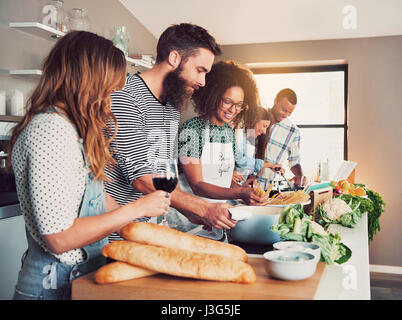 Große Gruppe von sechs Freunden, die Zubereitung von Speisen für einen Kochkurs am Tisch zu Hause oder in einer kleinen Kochschule Stockfoto