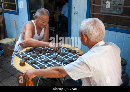 Dunhuang, China - 7. August 2012: Zwei chinesische Mann spielen chinesische Schach (Xiangqi) in einer Straße von der Stadt Dunhuang, China Stockfoto