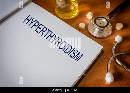 Hyperthyreose, geschrieben am Buch mit Tabletten. Medizin-Konzept Stockfoto