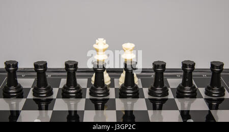 Konzept - acht schwarzen Türme befinden sich vor einem weißen Königin und König auf dem Schachbrett Stockfoto