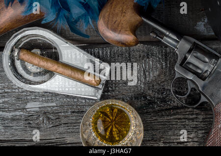 Thompson Gewehr, Revolver, Zigarre auf dem Whiskeyglas Aschenbecher und blauen Federboa Stockfoto