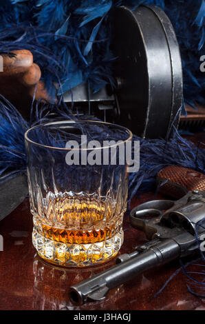 Thompson-Pistole, Revolver, Zigarren Aschenbecher, Whiskeyglas und blaue Federboa Stockfoto