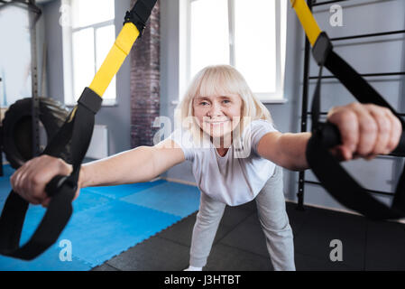 Übungen. Froh, dass positiv nach vorne beugen und die Ausübung während der Verwendung von Sportgeräten im Alter von Stockfoto