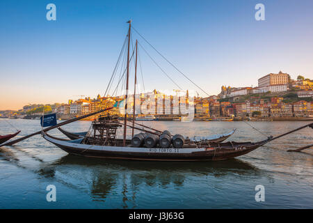 Douro Porto Portugal, Blick auf ein traditionelles Rabelo-Boot auf dem Douro-Fluss mit der Skyline von Porto bei Sonnenaufgang im Hintergrund, Portugal, Europa. Stockfoto