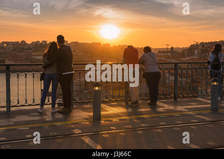 Romantische Reise, Rückansicht eines jungen Paares und eines Paares mittleren Alters, die nebeneinander stehen und einen Sonnenuntergang über einer europäischen Stadt, Europa, beobachten Stockfoto