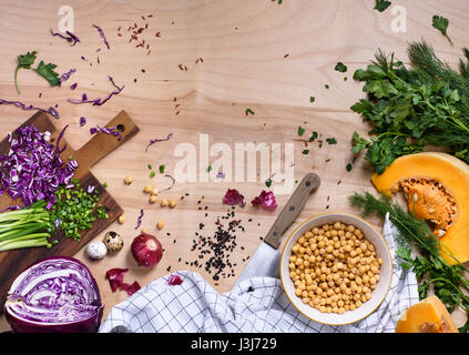 Saubere vegetarische Kost Konzept über natürlichen hölzernen Hintergrund, Ansicht von oben. Gemüse, Samen, Bohnen, Gewürze, Superfoods, Kräuter für Veganer, gesunde raw d Stockfoto