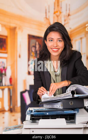 Junge lächelnde Geschäftsfrau mit Kopierer im Büro. Stockfoto