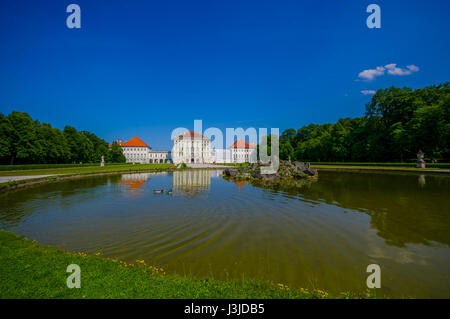 Nymphenburg, Deutschland - 30. Juli 2015: Schöne Palast wie aus Entfernung auf See, schöne Landschaften und die umliegenden grünen Gärten. Stockfoto