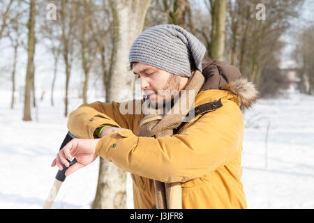 junger Mann entspannt vor Schnee Schaufeln Stockfoto