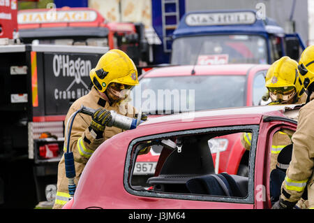 Firecrew aus Nordirland Feuer und Rettung Service zeigen, wie hydraulische Schneidausrüstung verwenden, um eine eingeschlossene Fahrer aus dem Auto nach frei ein Stockfoto