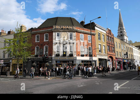 Masse der Leute auf der Straße im Frühjahr trinken Bier außerhalb Truman's Brewery Pub steht das Goldene Herz in Spitalfields East London KATHY DEWITT Stockfoto