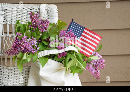 Amerikanische Flagge und lila Bouquet in hängenden Musselin Sack auf Korbstuhl Stockfoto