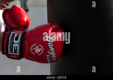 Junge Boxer mit roten Boxhandschuhe getroffen Boxsack. Stockfoto
