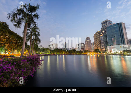 Malerische Aussicht auf den Benjakiti (Benjakitti) Park und beleuchteten Gebäude in Bangkok, Thailand, am Abend. Stockfoto