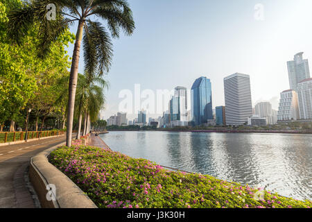 Jogging-Pfad, Blumenbeet und Bäumen an der Benjakiti (Benjakitti) Park und modernen Wolkenkratzern in Bangkok, Thailand. Stockfoto