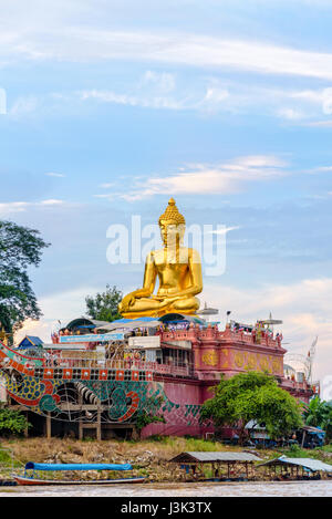 Schöne goldene Buddha-Statue Phra Buddha Nawa Lan Tue an den Ufern des Mekong-Flusses im Golden Triangle Park (Sob Ruak) im Laufe des Abends in C Stockfoto