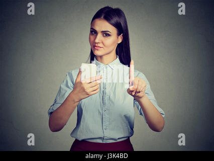 Junge strenge Frau mit Smartphone zeigen, Nein, nicht, Aufmerksamkeit mit Finger-Hand-Geste. Blockieren von Erwachsenen Inhalt, Kindersicherung Konzept Stockfoto