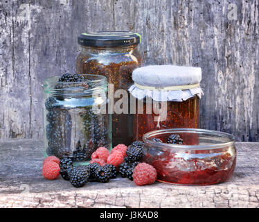 Topf mit Marmelade mit roten Früchten auf hölzernen Hintergrund Stockfoto