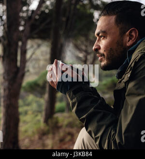 Richtungskontrolle junge männliche Wanderer trinken Kaffee hautnah. Männliche Wanderer Rast während der Wanderung. Stockfoto