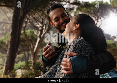 Junges Liebespaar camping im Wald und Kaffeetrinken. Junger Mann und Frau zusammen im freien lächelnd. Stockfoto