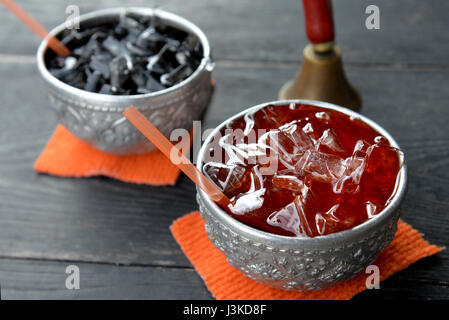 Schwarze oder rote Thai Eis Tee trinken auf dem silberne Schale servieren Thai-Stil Foto mit Outdoor-Sonne Beleuchtung. Stockfoto