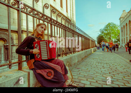 Paris, Frankreich 1. Juni 2015: Junge Zigeunerin auf Betonwand sitzen und spielen Akkordeon, böhmische Straße um berühmte Montmarte. Stockfoto