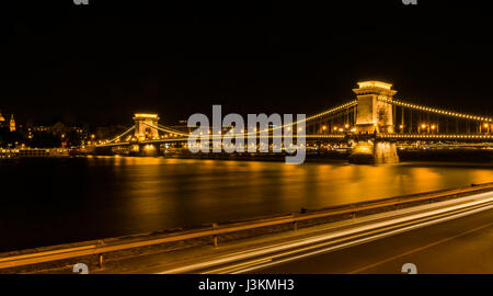 Night-Time-Ansicht der berühmten Kettenbrücke, die Donau mit der Brücke und Stadt Skyline von Budapest erstreckt beleuchtet im goldenen Licht. Stockfoto