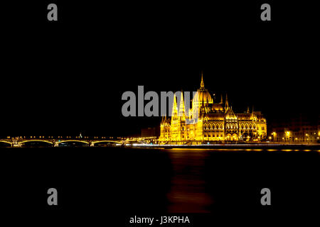 Das gotische ungarische Parlament Gebäude und in der Nähe der Brücke in der Nacht beleuchtet mit einem goldenen Glanz. Stockfoto