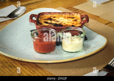 Klassische italienische Küche - Lasagne mit Fleisch in einer Schüssel Lehm mit geriebenen Tomaten und Parmesan Stockfoto