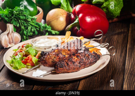 Schaschlik vom Grill serviert mit frittierten Pommes Frites und frischem Salat Stockfoto