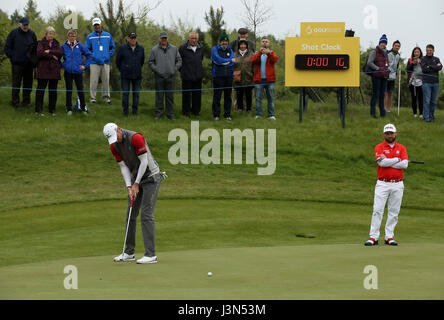 Englands Chris Wood spielt im Hintergrund Schuss mit der Uhr gedreht, als Andy Sullivan auf bei Tag eins der Golf-Sechser im Centurion Club, St Albans Uhren. Stockfoto