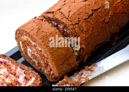 Scheiben von leckeren Schokolade Biskuit Rollen mit Sahne und Messer. Stockfoto