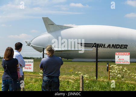 Cardington, Bedfordshire, UK. 7. Mai 2017. Die Hybrid-Luft Fahrzeuge Airlander 10 auf den neuen Mobile Mooring Mast in Cardington Flugplatz. Zuschauer die Aussicht genießen, während unerwünschte Eindringlinge als das Flugzeug Sicherheits-Sensoren auf Beiträge innerhalb des Zauns fernzuhalten, HAV 304 ist fast fertig, es ist 2017 Flugerprobungsprogramm beginnen. Bildnachweis: Mick Flynn/Alamy Live-Nachrichten Stockfoto