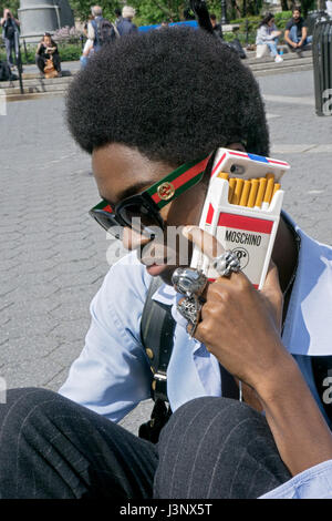 Porträt eines jungen Mannes mit einem ungewöhnlichen Handy Gehäuse gestellt. Union Square Park in Downtown Manhattan, New York City aufgenommen. Stockfoto