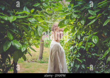 Heranwachsende Mädchen im grünen Garten, lächelnd in die Kamera Stockfoto