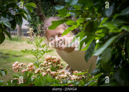 Heranwachsende Mädchen im grünen Frühlingsgarten, lächelnd in die Kamera Stockfoto